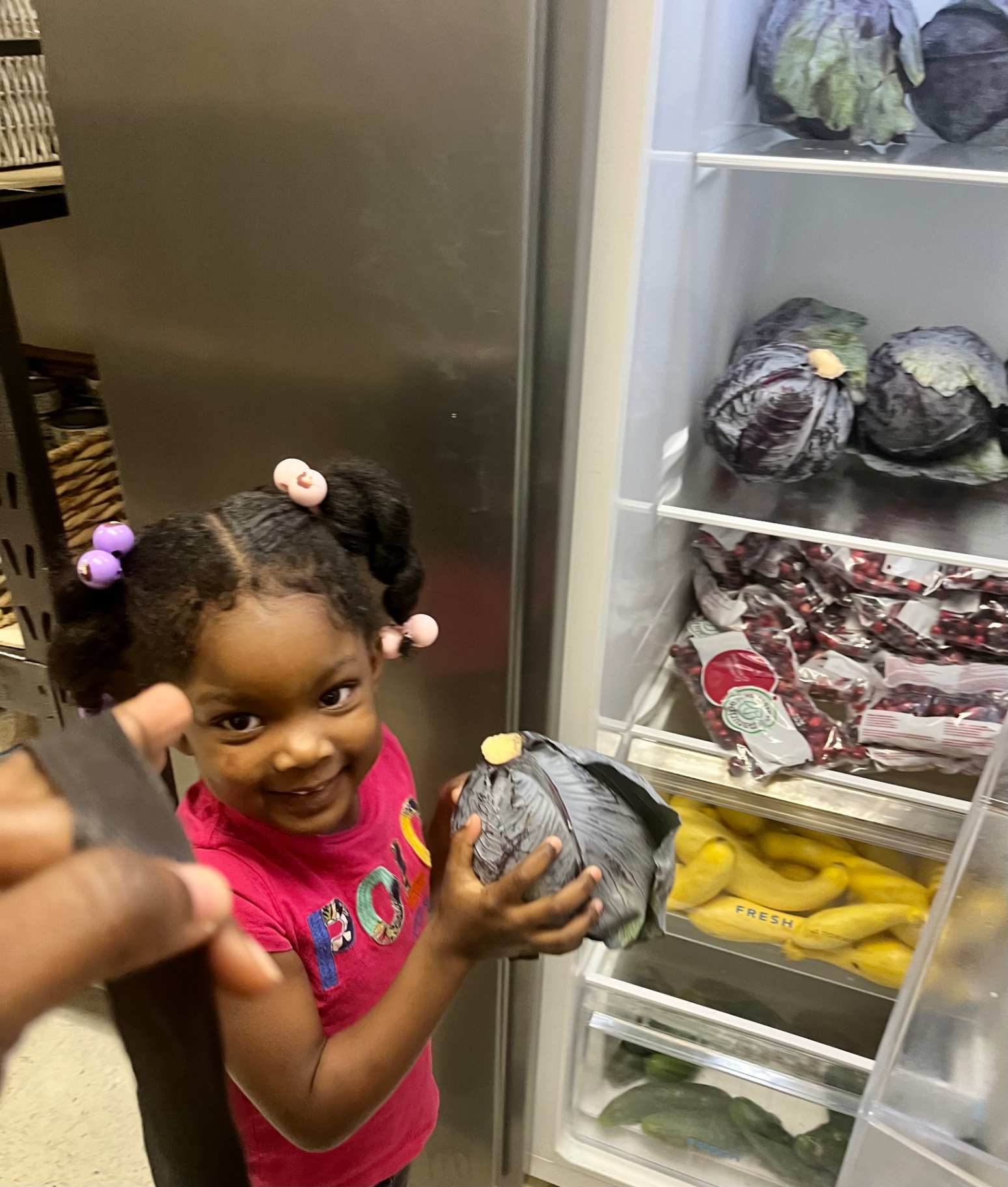 A young student proudly holding fresh produce from the pantry refrigerator
