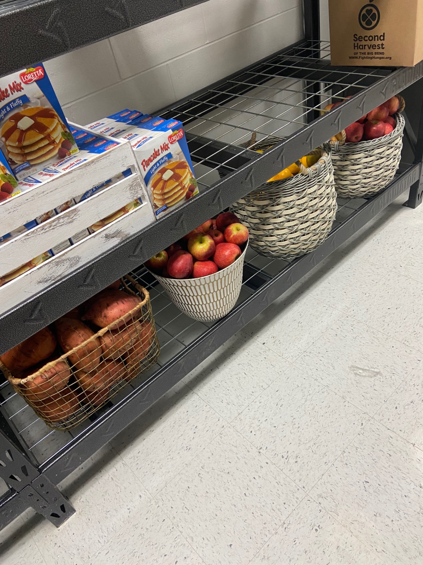 Fresh apples, sweet potatoes, and pantry staples stocked on the shelves